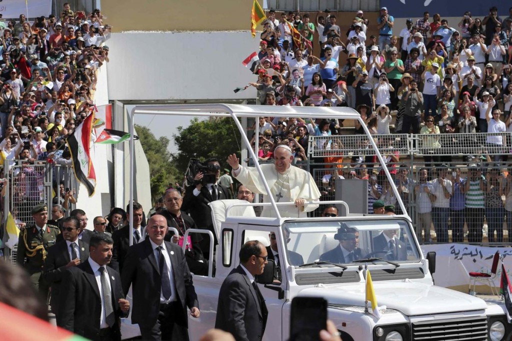 Pope waves to the faithful upon his arrival to attend a mass in Amman